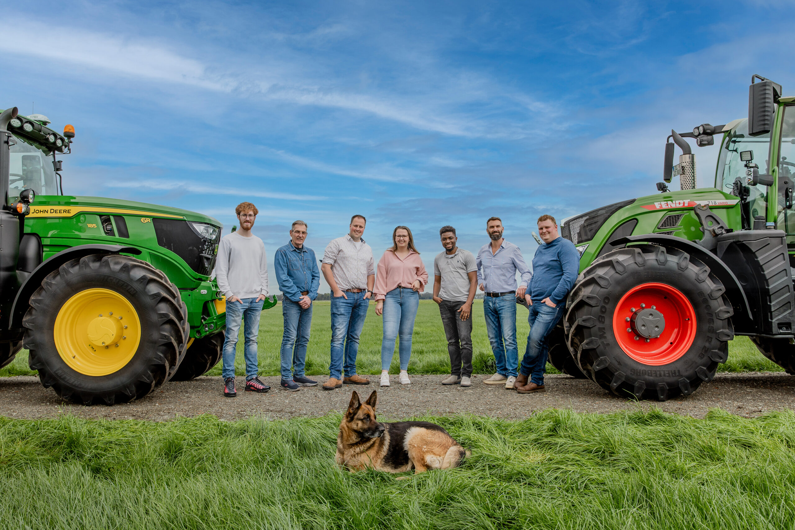 Équipe AgripoleD posant entre deux tracteurs (John Deere et Fendt) dans un champ, avec un chien au premier plan.